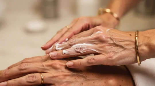 Primer plano de manos femeninas maduras mostrando signos de envejecimiento con tratamiento de belleza